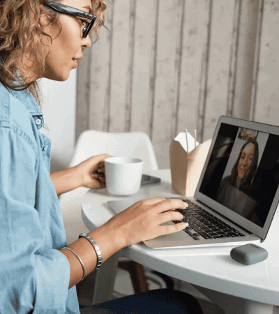woman using laptop for video call while drinking coffee